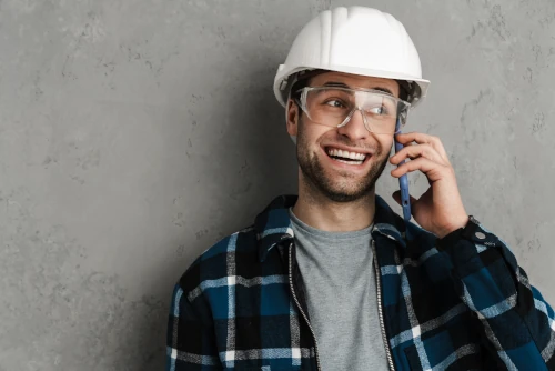 Friendly site coordinator with hard hat speaking on the phone – CTA image for GypsumWorks Malta.