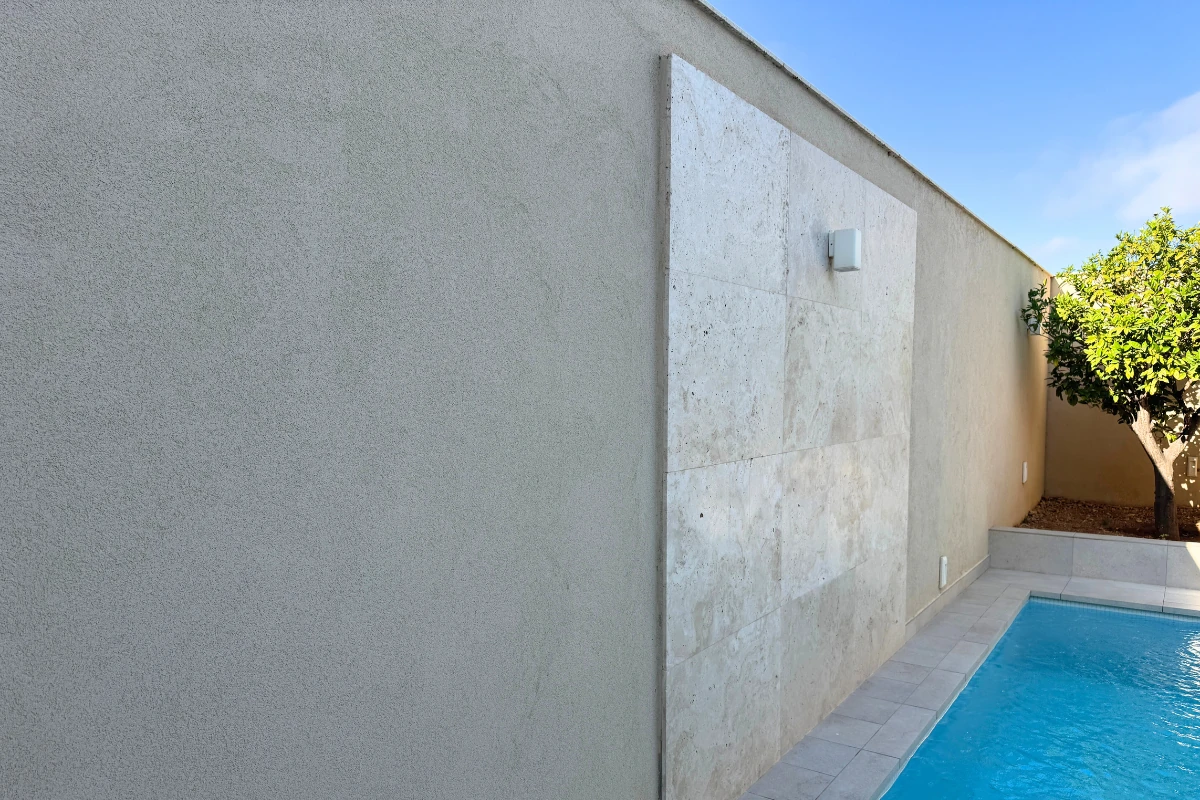 Exterior plaster finish on a garden wall beside pool area in Malta